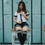 woman in white shirt and black shorts sitting on gray metal locker